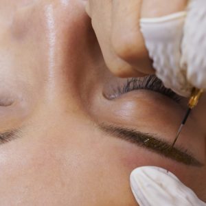 Young woman gets facial beauty procedure, microblading procedure on woman eye at beauty salon